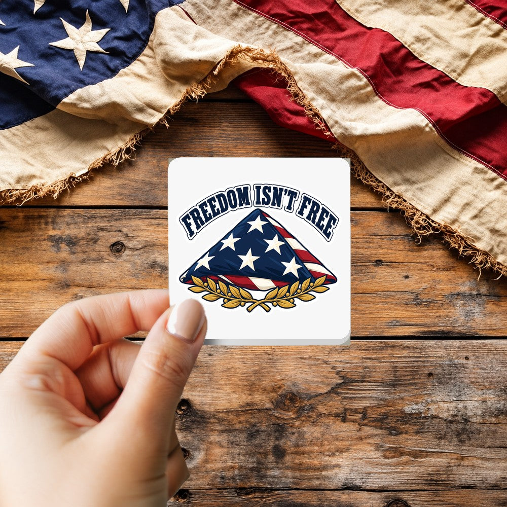 Freedom Isn't Free sticker held over a vintage American flag on rustic wood, Veterans Day gift
