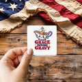 Grace Before Gravy sticker held over a vintage American flag on rustic wood, patriotic Thanksgiving gift