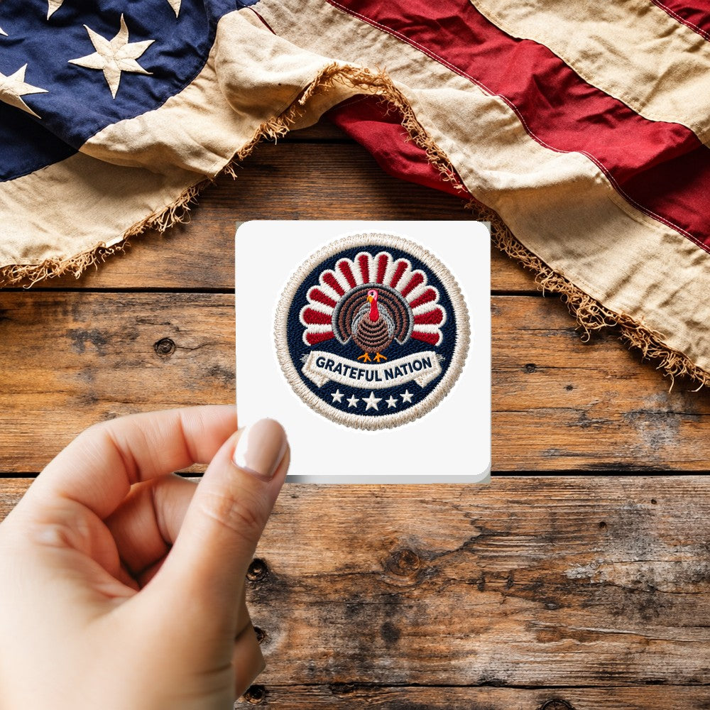 Grateful Nation sticker held over a vintage American flag on rustic wood, patriotic Thanksgiving gift