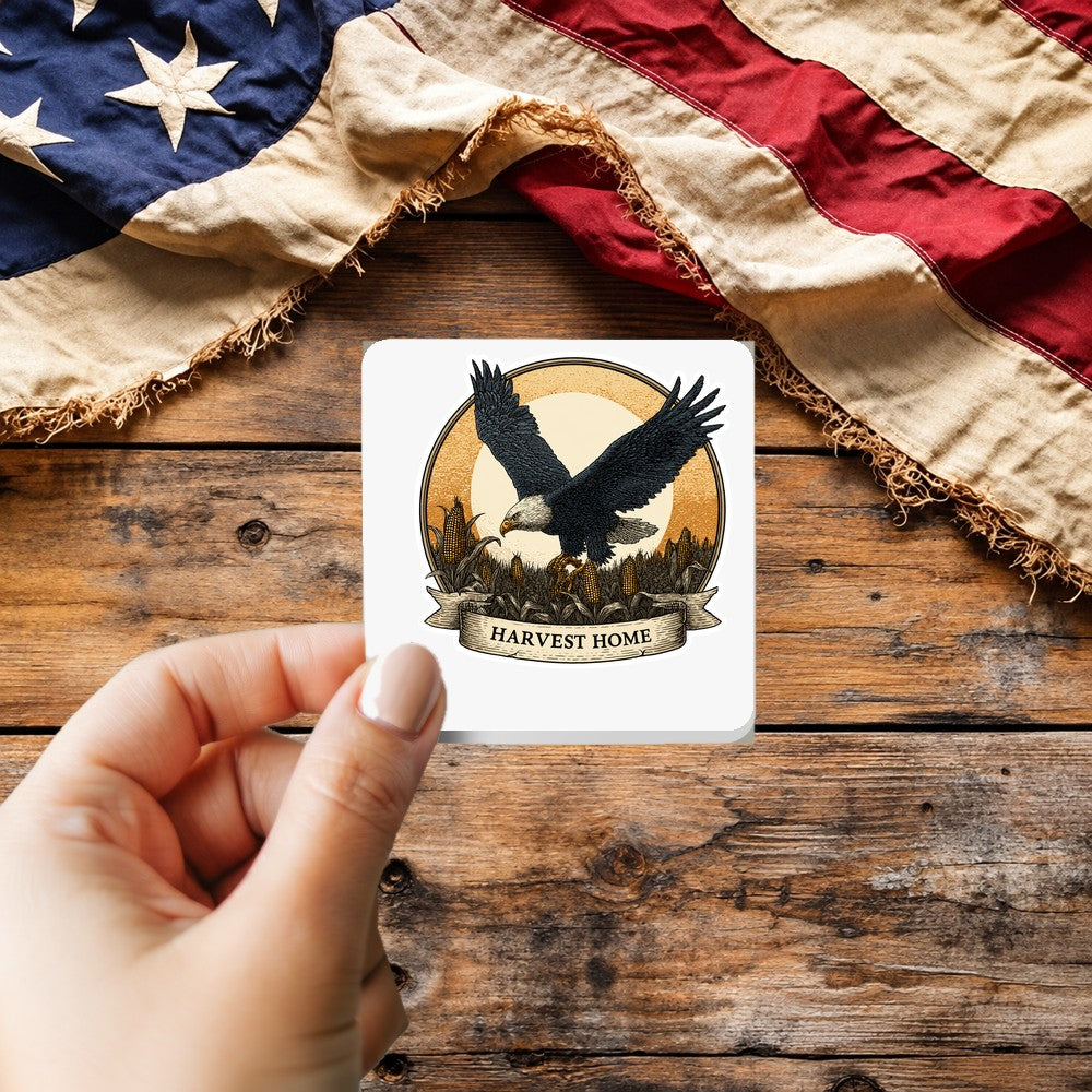Harvest Home Eagle sticker held over a vintage American flag on rustic wood, patriotic Thanksgiving gift