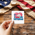 I Love My Veteran sticker held over a vintage American flag on rustic wood, Veterans Day gift