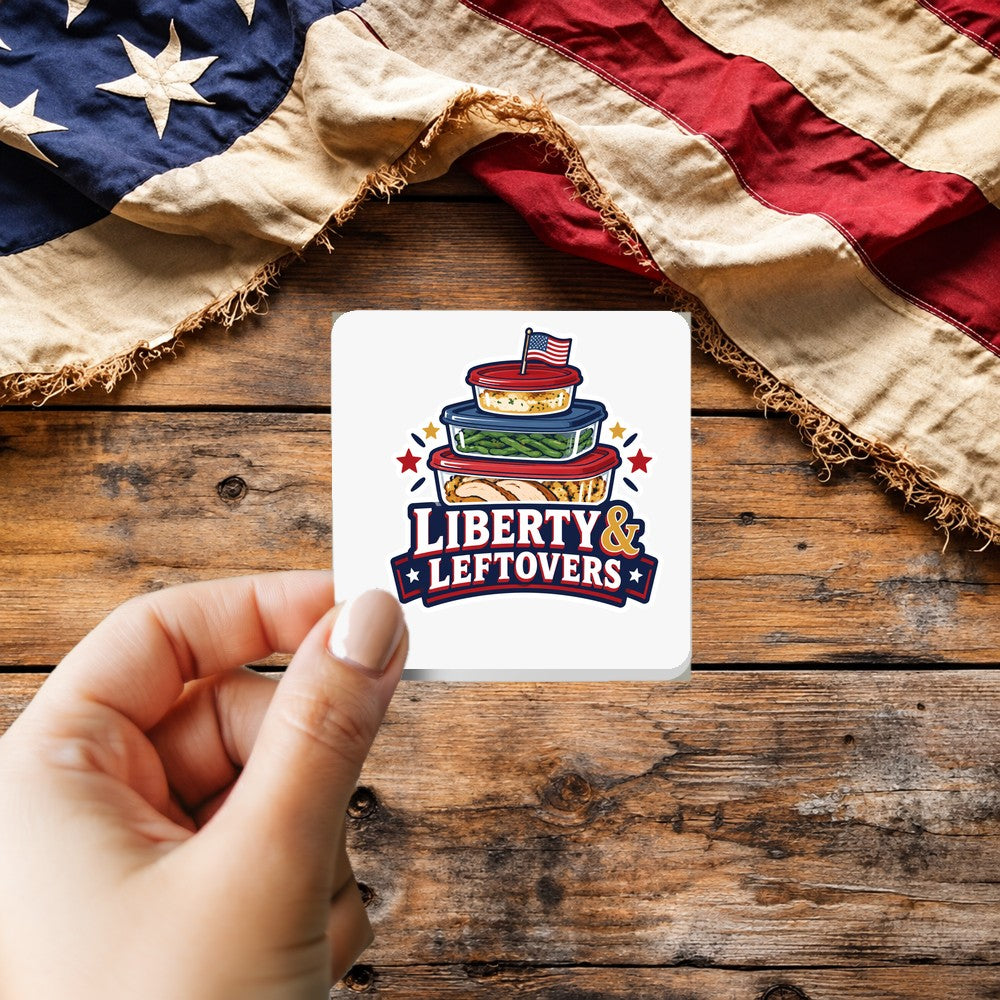 Liberty and Leftovers sticker held over a vintage American flag on rustic wood, patriotic Thanksgiving gift