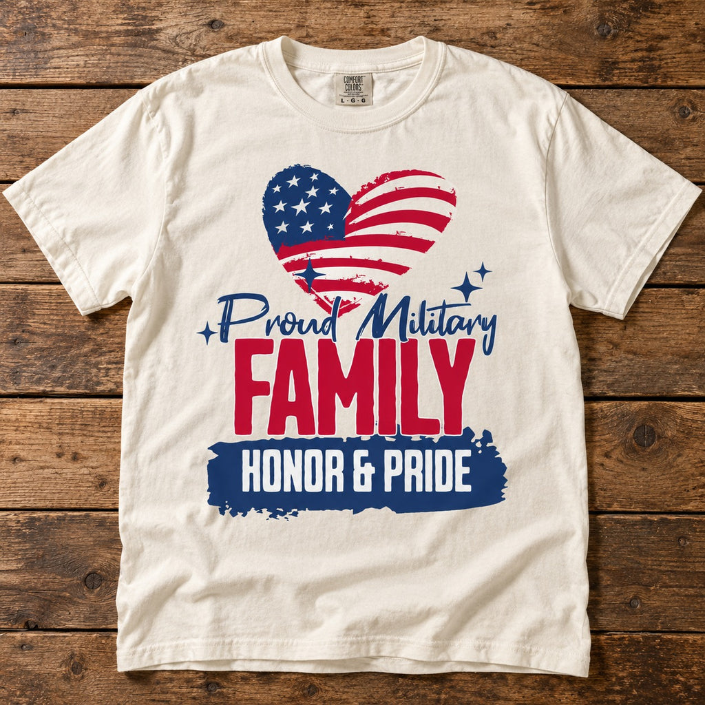 Proud Military Family shirt with an American flag heart, Proud Military script, red FAMILY lettering and HONOR & PRIDE banner, on an ivory tee laid on wood