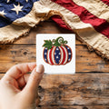 Stars and Stripes Pumpkin sticker held over a vintage American flag on rustic wood, patriotic Thanksgiving gift
