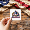 Thankful for Our Veterans sticker held over a vintage American flag on rustic wood, patriotic Thanksgiving gift