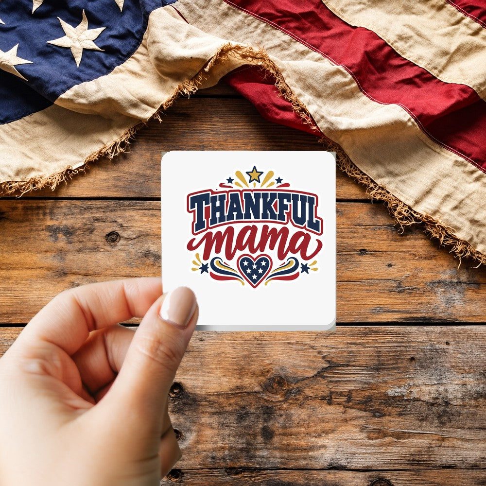 Thankful Mama sticker held over a vintage American flag on rustic wood, patriotic Thanksgiving gift