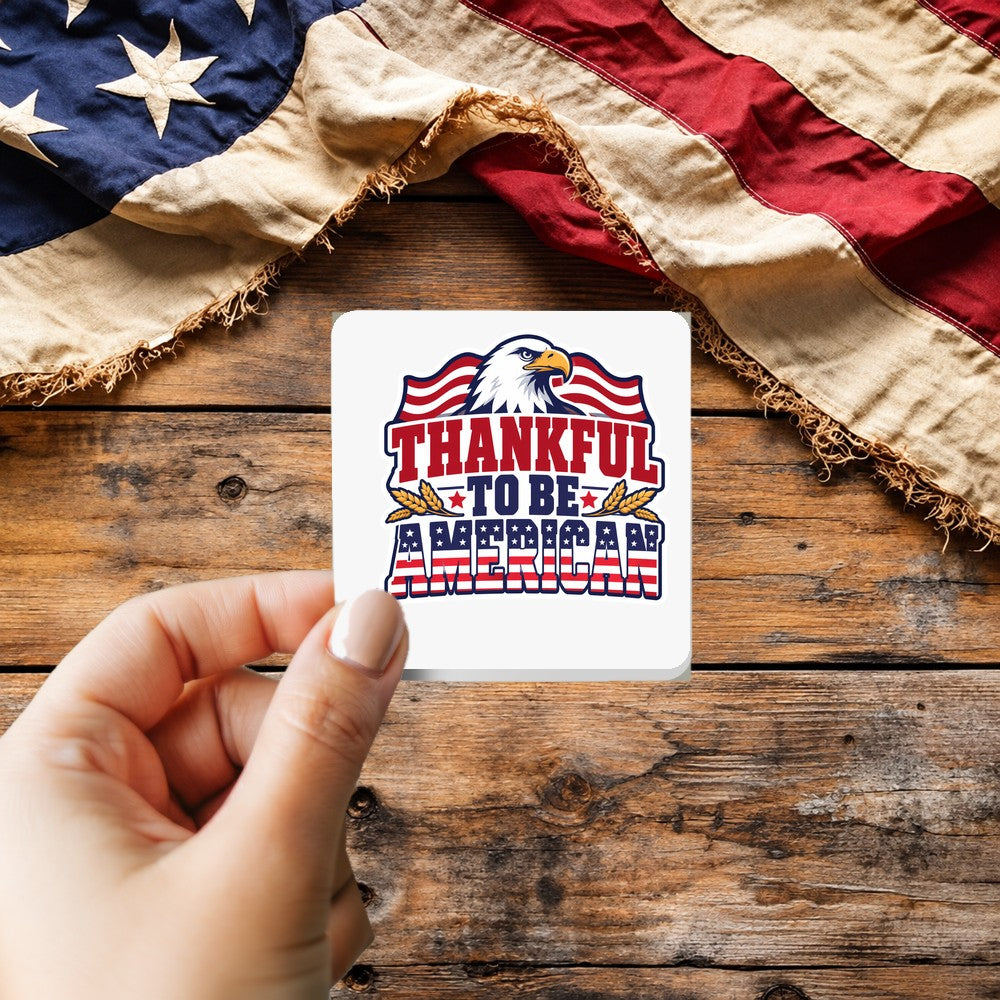Thankful to Be American sticker held over a vintage American flag on rustic wood, patriotic Thanksgiving gift