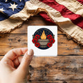 We Owe Them All sticker held over a vintage American flag on rustic wood, Veterans Day gift